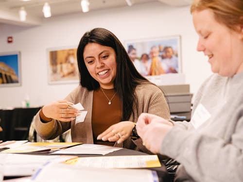 Two educators at a table adding sticky notes to a document