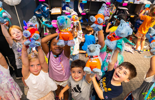 Group of excited young campers holding up stuffed griffins