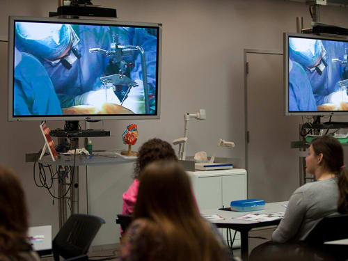 Students in classroom watching live heart surgery on screens