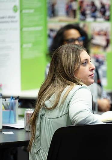 Educators in conference room focusing on an offscreen speaker