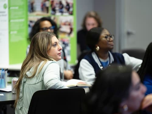 Educators in conference room focusing on an offscreen speaker