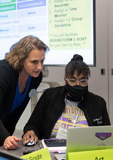 Griffin MSI instructor consults with seated teacher using laptop