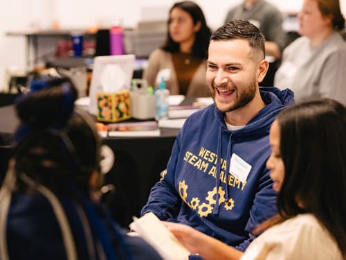 Educator laughing in conversation at conference table