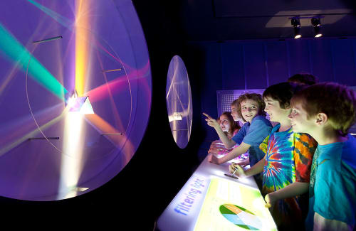 Group of young guests observing a prism splitting light into colors