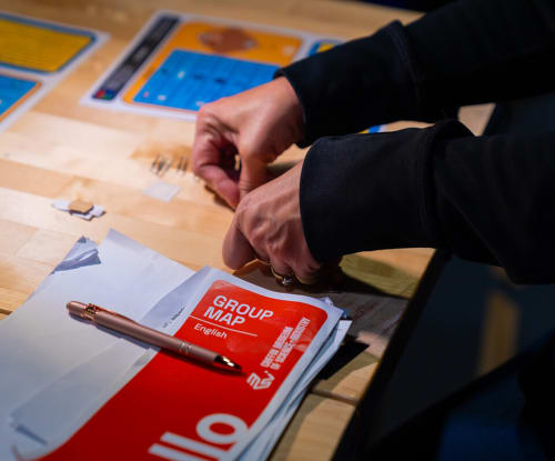 Pair of hands at a desk assembling a project with museum map nearby