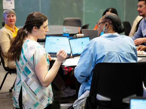 Griffin MSI instructor consults with seated teacher using laptop