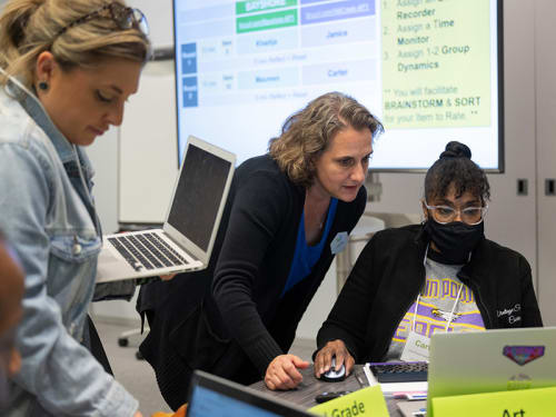 Griffin MSI instructor consults with seated teacher using laptop